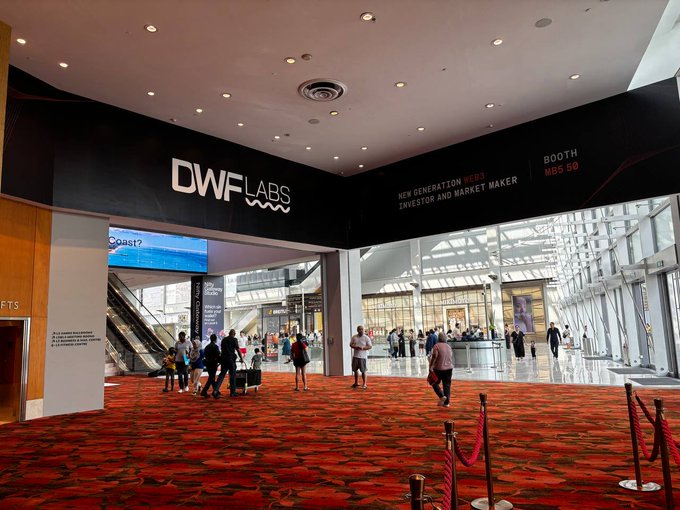 A large convention center entrance featuring a DWFLABS booth with the tagline 'NEW GENERATION WEB3 INVESTOR AND MARKET MAKER' and 'BOOTH MBS-50' displayed prominently above attendees on a red patterned carpet.