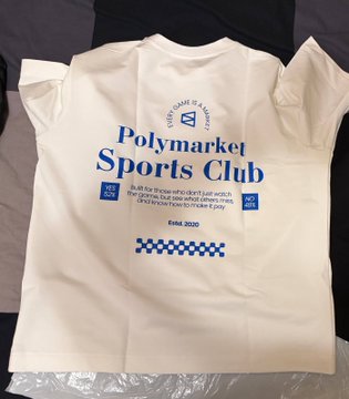 The image shows a white t-shirt with blue text that reads "Polymarket Sports Club", indicating that the shirt was made by this company for sports enthusiasts. The text also mentions that the shirt is "built for those who don't like watching games, but see what they're about to make a game". This suggests that the t-shirt might be designed to encourage people to engage in sports activities and spread awareness about Polymarket Sports Club among their friends or family members.