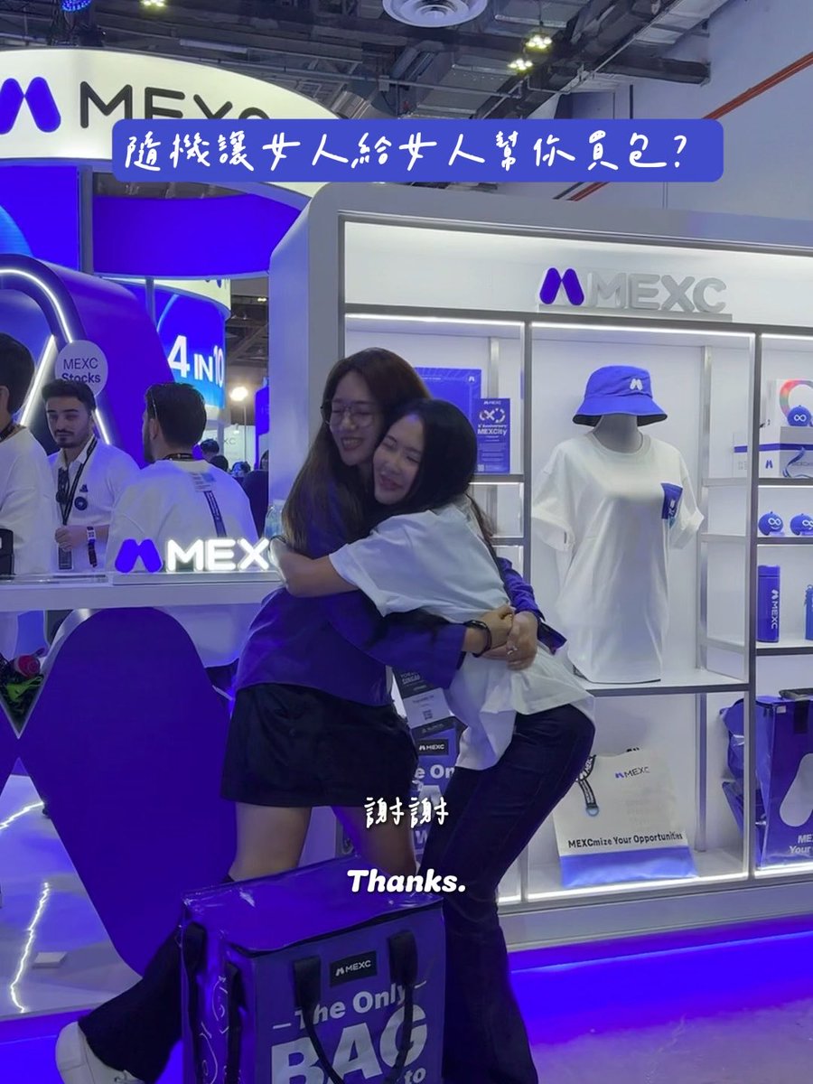 Two women hug at a MEXC cryptocurrency exchange booth, with Chinese text overlay asking '隨機選25人給25人幫你買包?' (Randomly select 25 people to help you buy a bag?), captioned 'Thanks.'