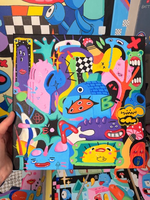 A vibrant, colorful piece of contemporary pop-art style artwork held by a hand, featuring cartoonish characters, abstract shapes, bold patterns including checkerboards, and expressive faces in pink, blue, yellow, and other bright colors on a black background.