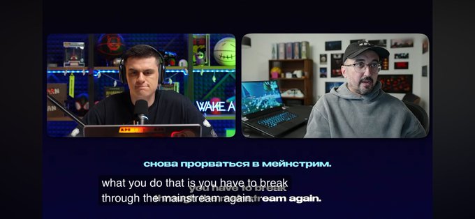 Two men appear in a podcast/video format with Russian and English subtitles discussing breaking through the mainstream media, with text reading 'снова прорваться в мейнстрим.' and 'what you do that is you have to break through the mainstream again, dream again.'