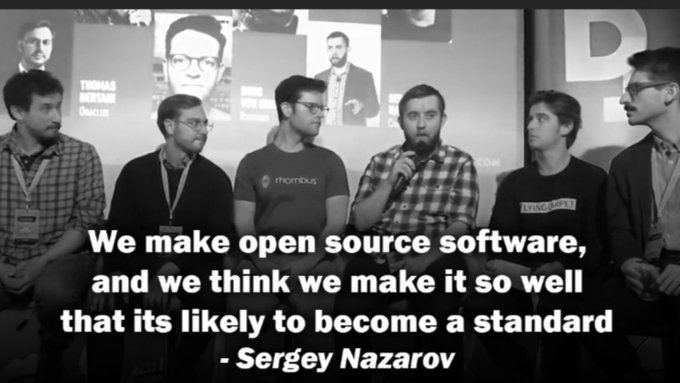 A black-and-white photo of several men seated on a panel, with the quote: 'We make open source software, and we think we make it so well that its likely to become a standard - Sergey Nazarov'.