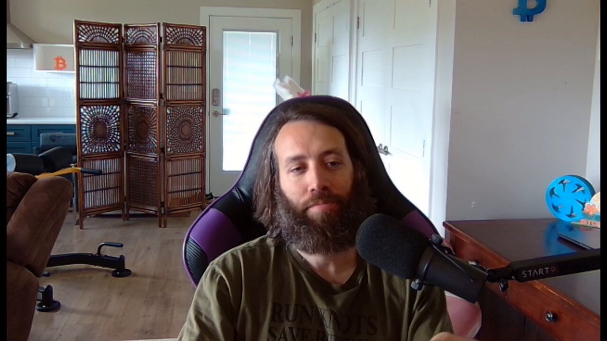 The image shows a man sitting in a chair with a microphone in front of him, suggesting that he might be hosting or participating in an online event such as a podcast or live stream. The caption reads "Mechanic banned from r/Bitcoin for referring to bip110 miner signaling", which implies that the man has been banned from a specific subreddit due to making a controversial statement about Bitcoin mining. This restriction is enforced by the subreddit's policies, which aim to maintain a respectful and inclusive environment for its members.