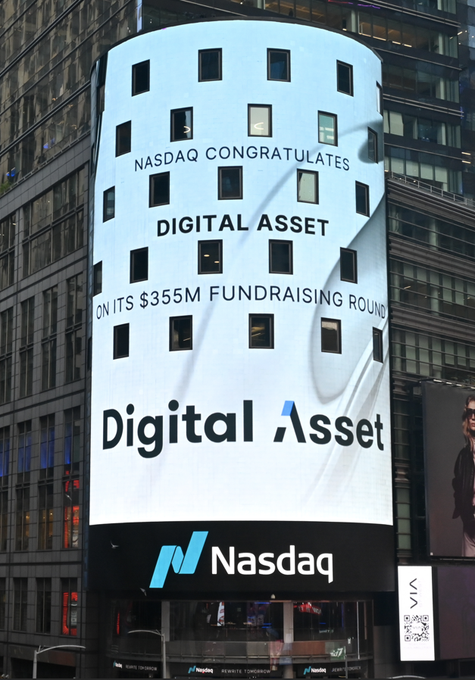 The image features a large white building with a digital asset sign on top that reads "Digital Asset" along with some text about fundraising rounds. The building also has a banner advertising the Nasdaq company, which is located below the digital asset sign. In front of the building, there are two cars parked and people walking around in the background.