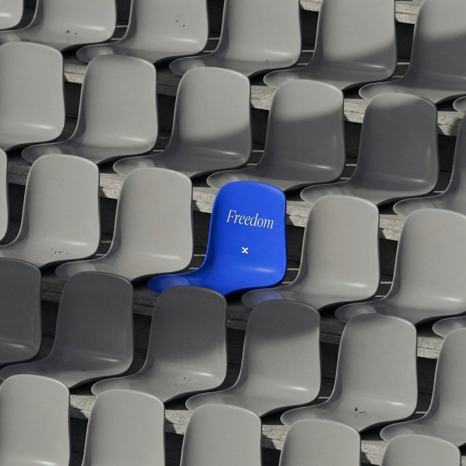 A single bright blue stadium seat labeled "Freedom" stands out among rows of empty gray seats, perfectly matching the post's invitation to "take a seat, we've got the spot you're looking for."