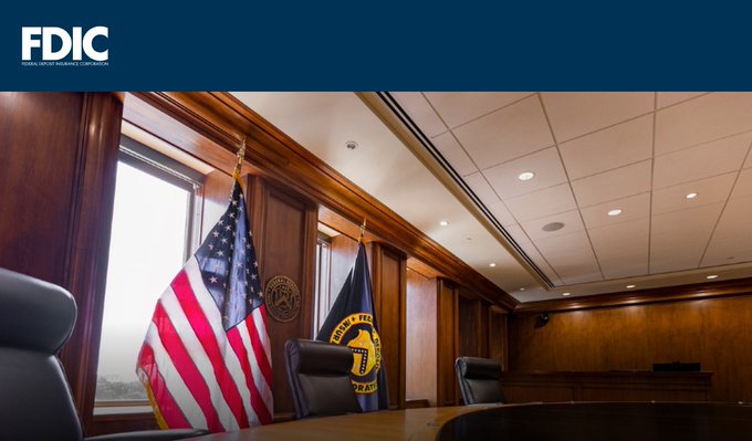 We need to write a concise 1-2 sentence caption describing what's in the image, including any key text, numbers, tickers, names visible. Also note how image relates to the post.

Image: FDIC logo top left. Inside a formal meeting room with wood paneling, flags: US flag and FDIC flag (with seal). Text "FDIC" and "Federal Deposit Insurance Corporation". Also "UNITED STATES OF AMERICA" maybe on seal. Also "FEDERAL DEPOSIT INSURANCE CORPORATION" maybe on flag. The caption should mention FDIC, meeting room, flags, etc.

Post context: It's about new regulation, industry letters to FDIC, comments received, GENIUS Act, stablecoins, Ripple, etc. So image relates as FDIC is the regulator.

Thus caption: "A formal FDIC conference room with wood paneling, the American and FDIC flags