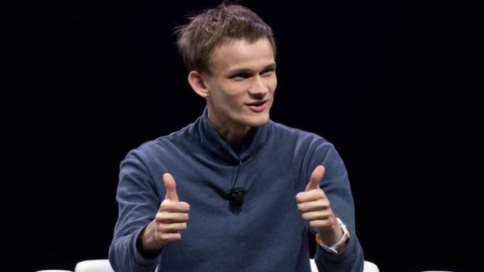 Vitalik Buterin, the co-founder of Ethereum, gives two thumbs up while speaking on a stage against a black background.