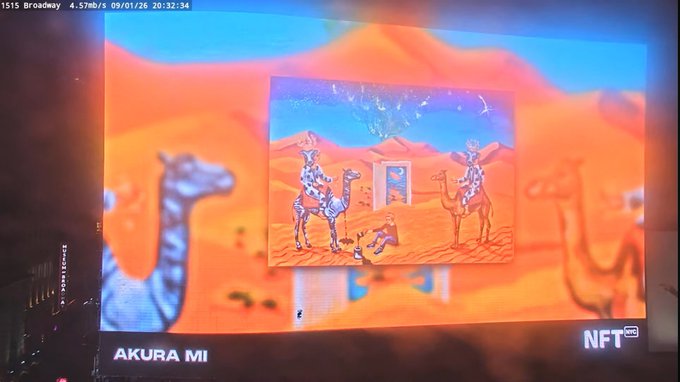 A photograph of a digital billboard displaying an NFT artwork titled 'AKURA MI' that depicts figures riding camels in a desert landscape with vibrant orange sand dunes.