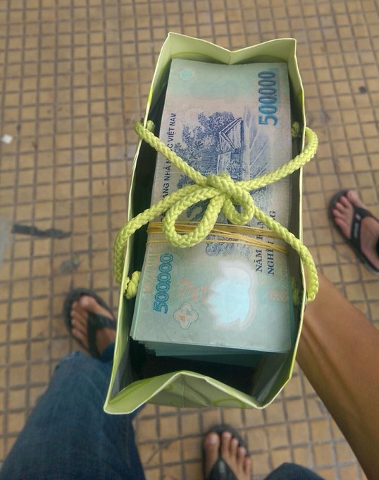 The image shows two people standing next to each other with their hands on a green bag filled with money. The person on the left side of the image has their hand on the bag, while the person on the right side has their foot resting on the bag. There are also some text elements in the image that read "buy a house, buy a car, or buy Bitcoin, brothers." This suggests that they might be discussing financial matters or planning to invest in something related to real estate, vehicles, or cryptocurrency.