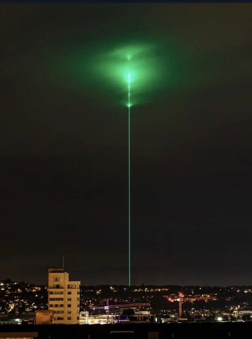 A powerful green laser beam shoots into the night sky from above a cityscape, illuminating the clouds with an otherworldly glow. The dramatic vertical streak visually mirrors the post's question about whether $HYPE and $SOL will surge to $150 this week—both the image and the caption evoke a sense of something piercing upward with intensity and momentum.