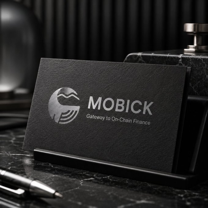 A sleek, dark grey business card standing upright on a black marble surface, featuring a silver logo and the text 'MOBICK Gateway to On-Chain Finance' in metallic lettering.