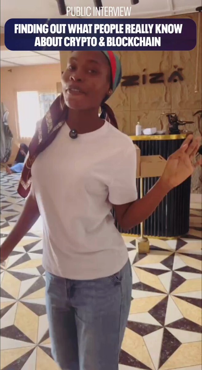 The image features a woman standing on a tiled floor, wearing a white shirt and blue jeans. She has her arms raised above her head as if she's posing for a photo or giving an interview. The background of the image shows a wall with a sign that reads "Public Interview".