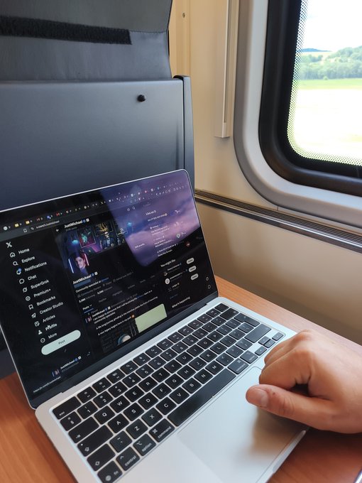 A person uses their laptop on a train, with the X (formerly Twitter) interface visible on screen, to spread awareness about Trezor cryptocurrency hardware wallets. The image shows digital advocacy in action—sharing crypto security knowledge while traveling.