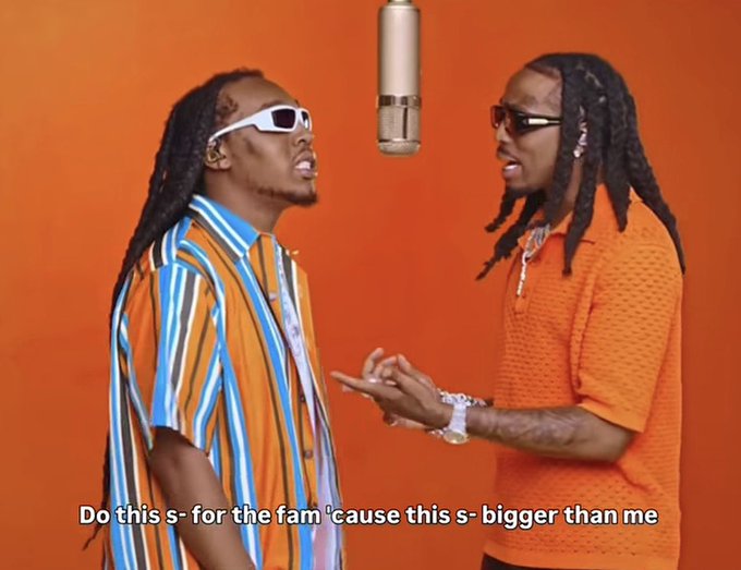 Two men with dreadlocks and sunglasses face each other near a hanging microphone against an orange background, with lyrics reading 'Do this s- for the fam 'cause this s- bigger than me.'