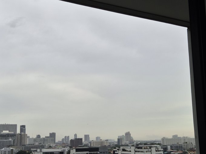 A view from a high-rise window overlooking a city skyline under an overcast, gray sky.