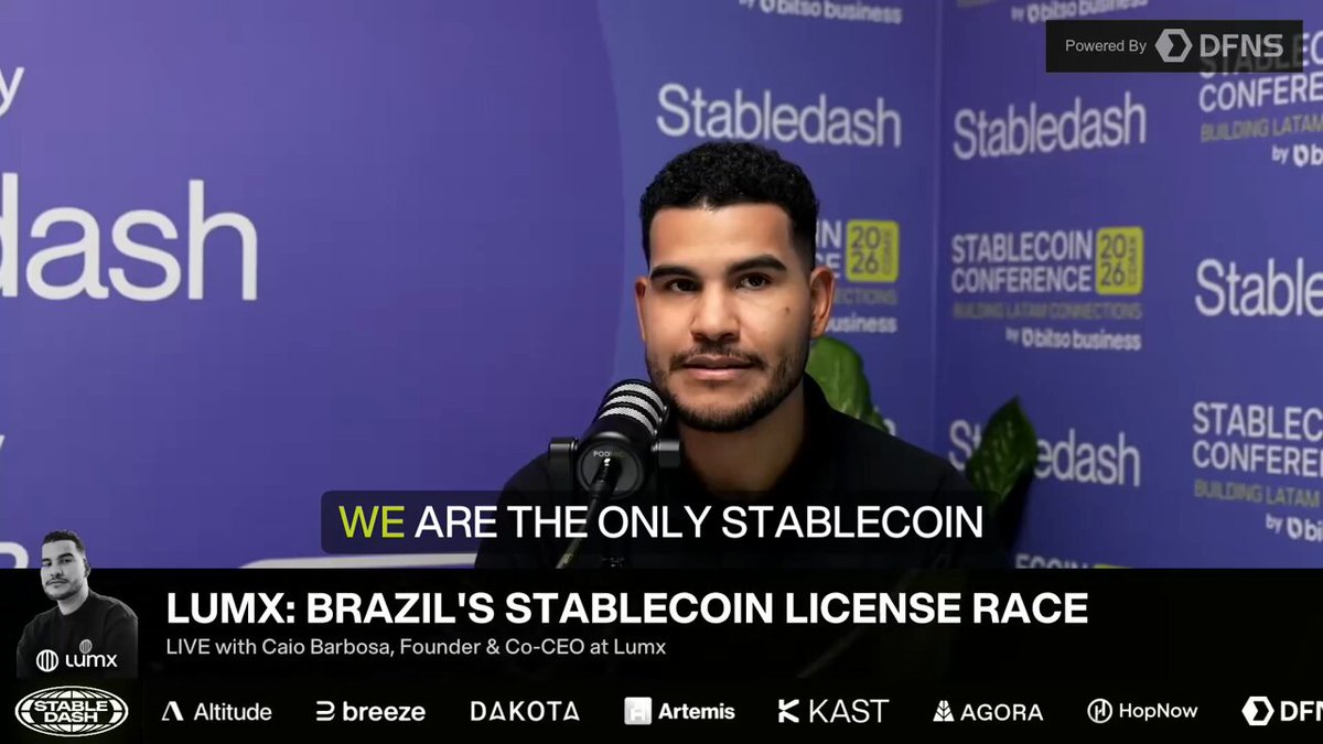 The image features a man sitting behind a microphone at a conference, with a purple background that includes text about Lumx's Brazilian Stablecoin license race. The caption reads "We are the only stabelec coin Lumx's Brazilian Stablecoin License Race", which is related to the post in question.