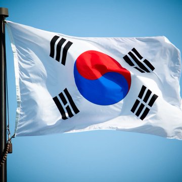 The South Korean flag waves against a clear blue sky, symbolizing the nation that has just blocked access to the prediction platform Polymarket due to illegal gambling concerns. The image directly represents the country enforcing regulatory action against the online betting service.
