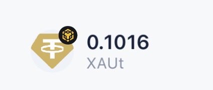 A logo with a gold hexagon featuring a bull icon next to the text '0.1016 XAUt', representing a gold token price.