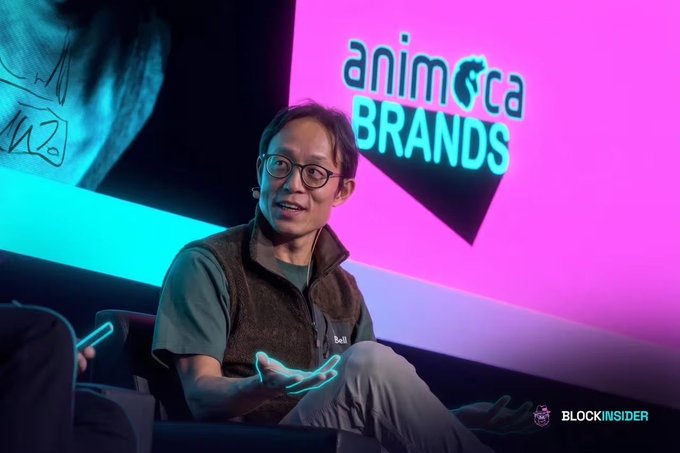 A man identified as "Bill" sits on stage at an "Animoca Brands" event, gesturing as he speaks, with a pink backdrop featuring the company logo and a "BlockInsider" watermark in the corner. The image illustrates the post's theme of a calm expert analyzing the crypto market's anxiety despite strong fundamentals.