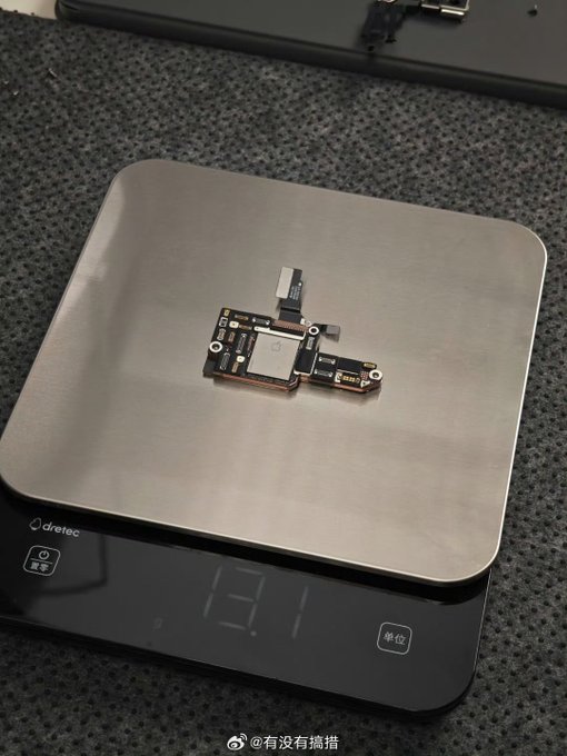 A small electronic component, likely from an Apple device, sits on a silver Dretec digital kitchen scale displaying a weight of '13.1'.