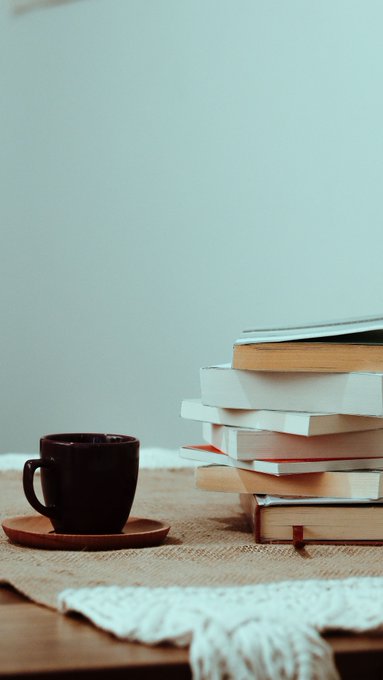 A dark mug sits beside a stack of books on a woven mat, suggesting a quiet reading scene. The cozy, reflective setting complements the post's tone of looking back on a multifaceted career and contemplating its unpredictable chapters.