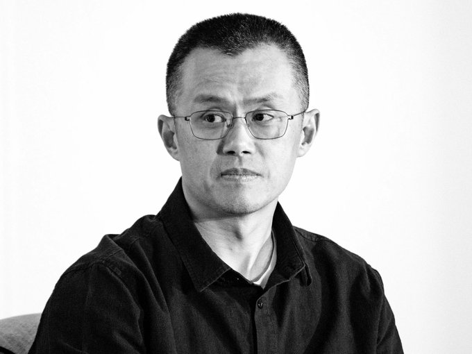 A black and white portrait of a middle-aged man with glasses and short hair wearing a dark button-up shirt.