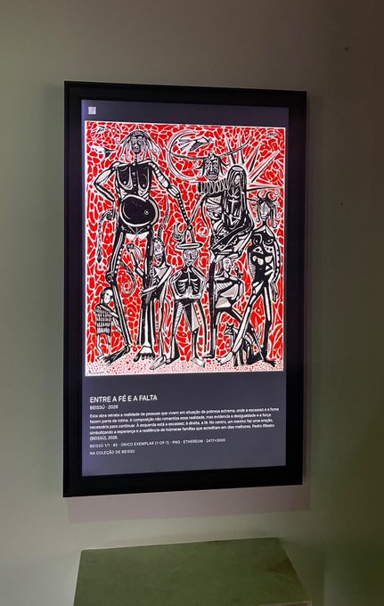A framed artwork titled "ENTRE A FÉ E A FALTA" (Between Faith and Scarcity) by Bêju, dated 2020, is displayed on a gallery wall at Casa NUA in São Paulo, Brazil. The piece features bold black figurative drawings against a vibrant red background, with accompanying text describing it as acrylic and graphite on canvas measuring 60 x 47 cm, signed and numbered 17/40, and on loan from the artist's collection as indicated by "NA COLEÇÃO DE BEJU."