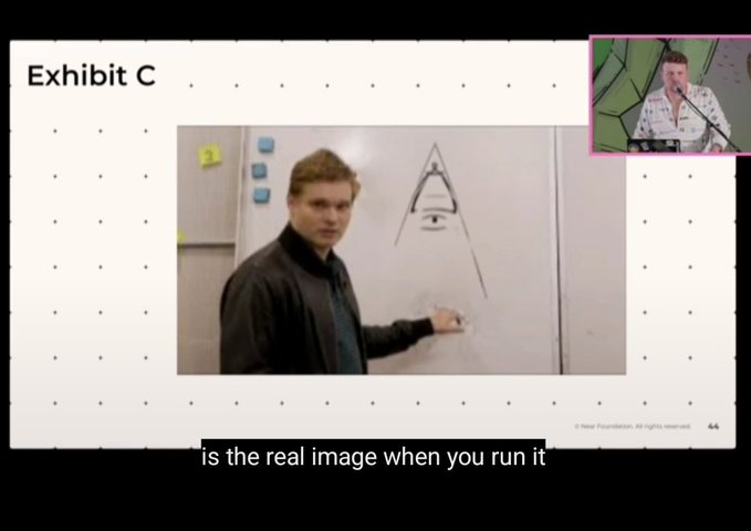 A presentation slide titled 'Exhibit C' showing a man standing next to a whiteboard drawing of a pyramid/triangle with an eye, with caption text 'is the real image when you run it' and a small video feed of another speaker in the top right corner.