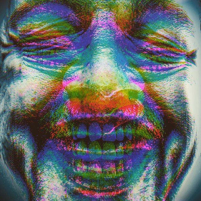 A distorted, psychedelic close-up portrait of a face rendered in vivid multicolored hues, showing closed eyes and an open mouth, with an AI-generated glitch aesthetic.