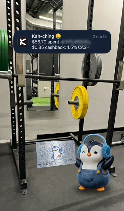 The image shows a KAST Visa card with a penguin design on the floor of a gym, alongside a 3D animated penguin wearing headphones, with a notification at the top showing a $56.79 gym membership transaction earning $0.85 cashback (1.5%). The scene visually ties together the gym payment, KAST card, and Pudgy Penguins branding from the post.