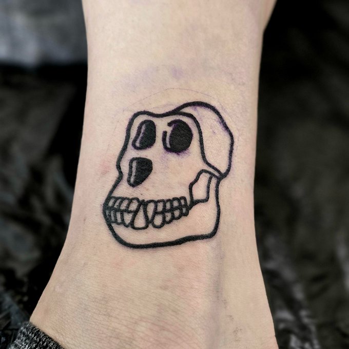 A close-up of a small skull tattoo inked on a person's wrist.