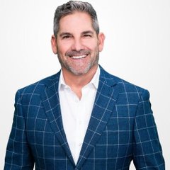 A smiling man with salt-and-pepper hair and a beard, wearing a blue checkered blazer over a white shirt, poses against a white background—likely Grant Cardone, the founder of Cardone Capital highlighted in the post about the company's $26.9 million Bitcoin purchase.