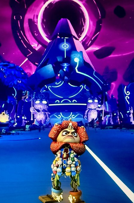 A video game screenshot featuring a small character with a mushroom-like head standing before a large, glowing blue and purple pyramid structure with mystical symbols.