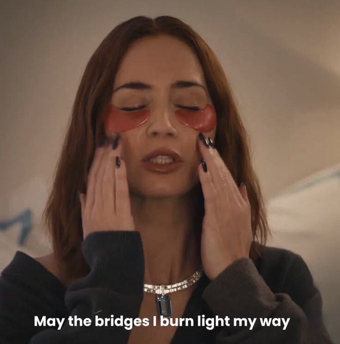 A young woman with brown hair applies under-eye patches with her eyes closed; the caption reads 'May the bridges I burn light my way.'