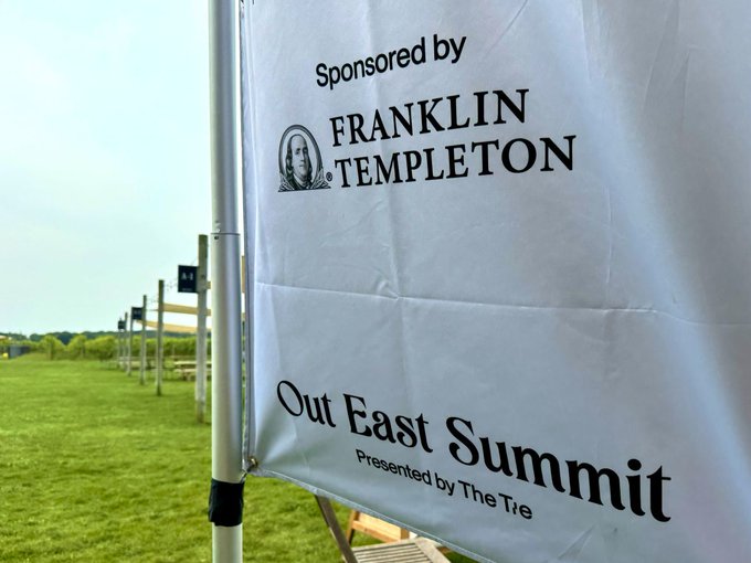 A white banner sponsored by Franklin Templeton promotes the "Out East Summit," presented by The Tie, displayed at an outdoor venue with grass and other banners visible in the background, fitting a casual "gm" (good morning) post.