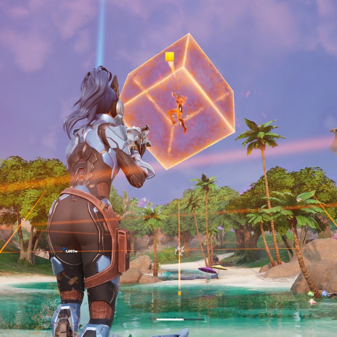 A female character in futuristic armor aims a glowing weapon at an opponent inside a holographic cube in a tropical Fortnite landscape, with "1,007m" displayed on screen—a nod to the "Midas or whatever" caption, likely referencing the Midas skin that once famously used a gold cube structure in-game.