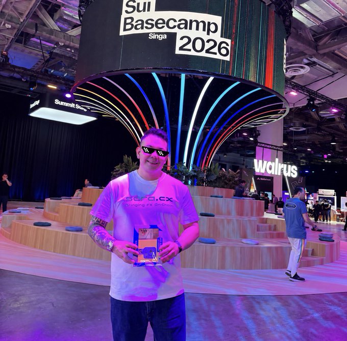 A man wearing a Sui Basecamp Singapore 2026 shirt and sunglasses holding an award at the Sui Basecamp 2026 conference, with a Walrus booth visible behind him.