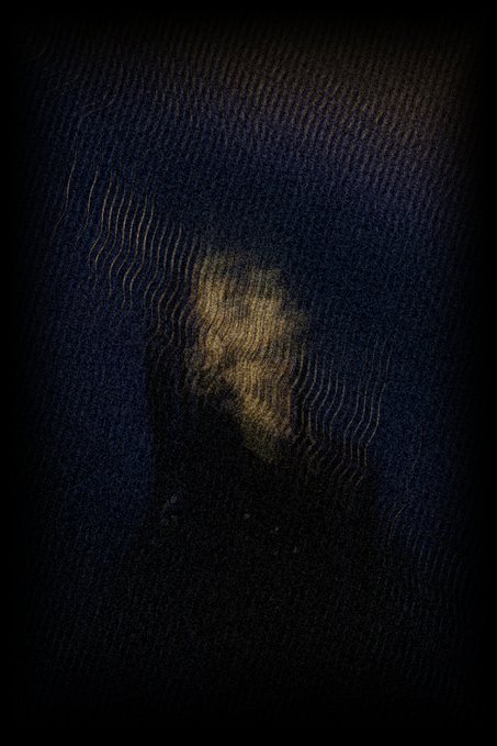 A worn, dark denim fabric is illuminated by a faint golden patch in the center, evoking a sense of concealment and quiet mystery. The interplay of shadow and subtle light on the rough texture mirrors the post's theme of surrender and obscurity, with the "0.15 eth reserve" hinting at hidden value resting in darkness.