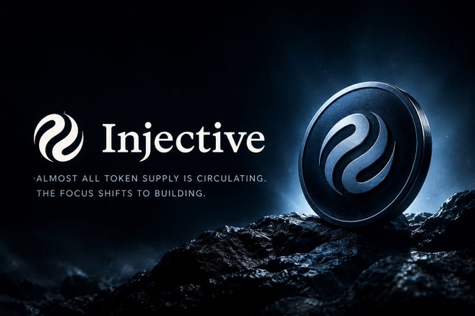 The image features a coin with the word "Injective" written on it, sitting atop a rock. The background of the image is dark blue, which contrasts with the white text on the coin. Below the coin, there's some text that reads "Almost all token supply is circulating. The focus shifts to building". This text seems to be related to the concept of token circulation and its impact on the crypto world.