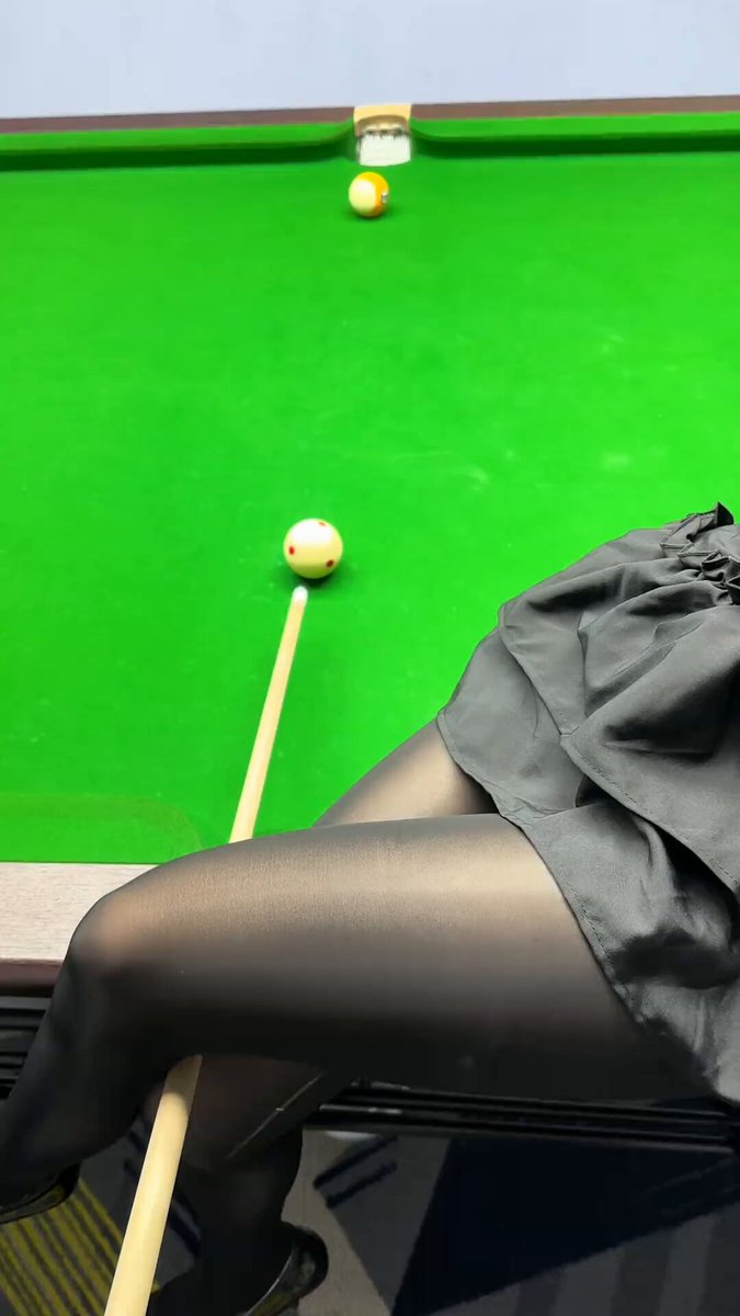 The image shows a woman sitting at a pool table with her legs crossed while holding a pool stick. The green table has two balls on it, one of which she is aiming for. The scene takes place during the evening hours, as indicated by the time stamp in the caption. The image also contains text that reads "It'S Thursday again—tonight at 9 PM, come join @TermMaxFi's DC for a battle royale game, with a chance to win cash prizes". This suggests that the woman is participating in an online gaming event or gathering during the evening hours.