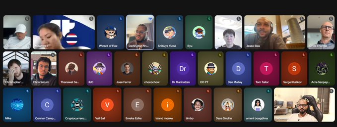 A screen showing a virtual meeting or video call with numerous participants represented by avatars or camera feeds, including names like 'Wizard of Poz', 'Shibuya Yuma', and 'Jesse Biles'.
