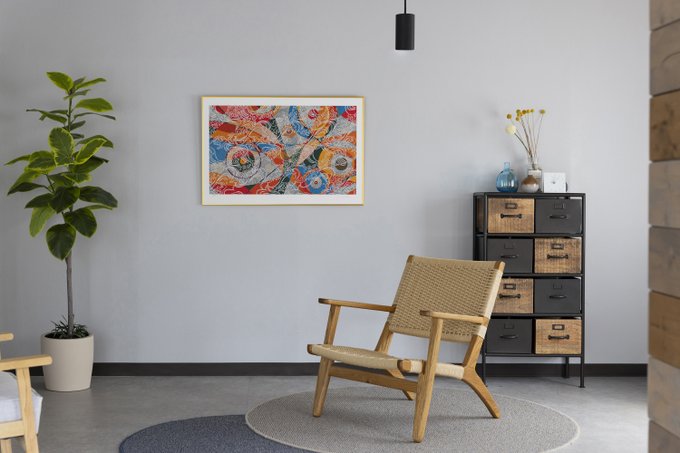 A modern interior space features a woven wooden chair on a circular rug, a colorful abstract framed painting on a gray wall, a tall potted plant, and a multi-drawer cabinet.