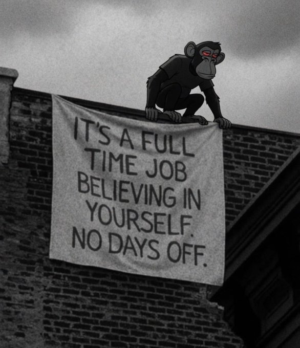 A black-and-white photo shows a monkey with red eyes perched on a rooftop holding a banner that reads "IT'S A FULL TIME JOB BELIEVING IN YOURSELF. NO DAYS OFF."