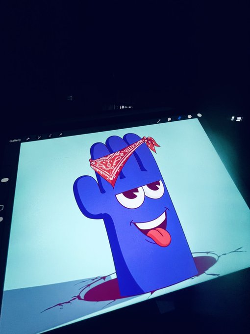 A digital illustration on a screen depicts a blue cactus-like character wearing a red bandana, smiling with its tongue out and emerging from cracked ground.