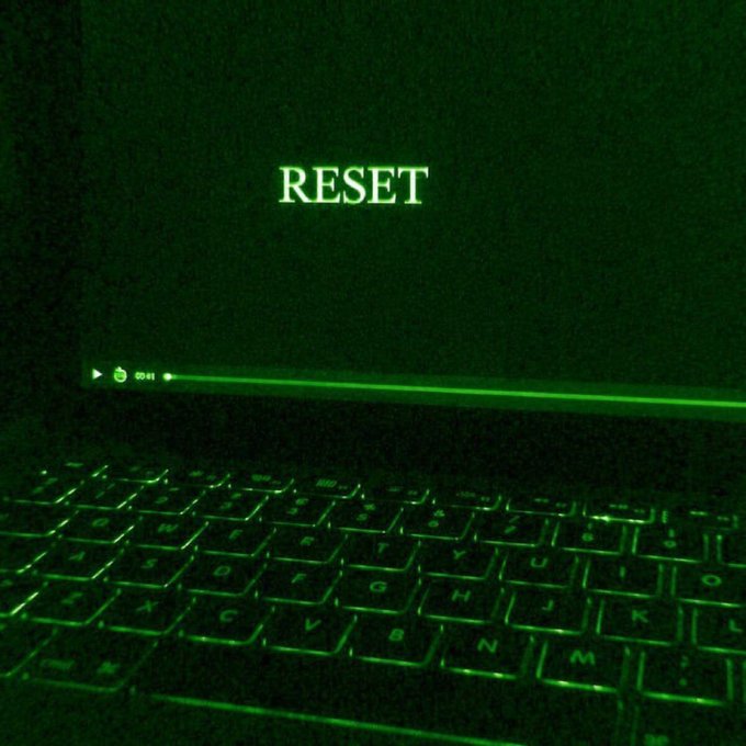 A laptop screen glows green in a dark room, displaying the word 'RESET' above a progress line at 0:41, with a backlit green keyboard in the foreground.