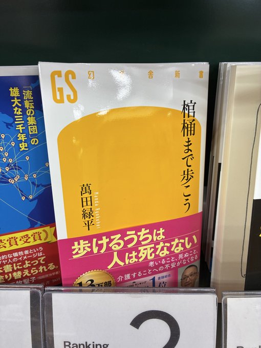 The image shows a book titled "GS" with an orange cover, sitting among other books on a shelf. The book has Japanese text written on its spine, indicating that it might be intended for readers who speak or understand Japanese. The post also includes information about banking and a number 2, which could possibly be related to the book's content or the context of the image.
