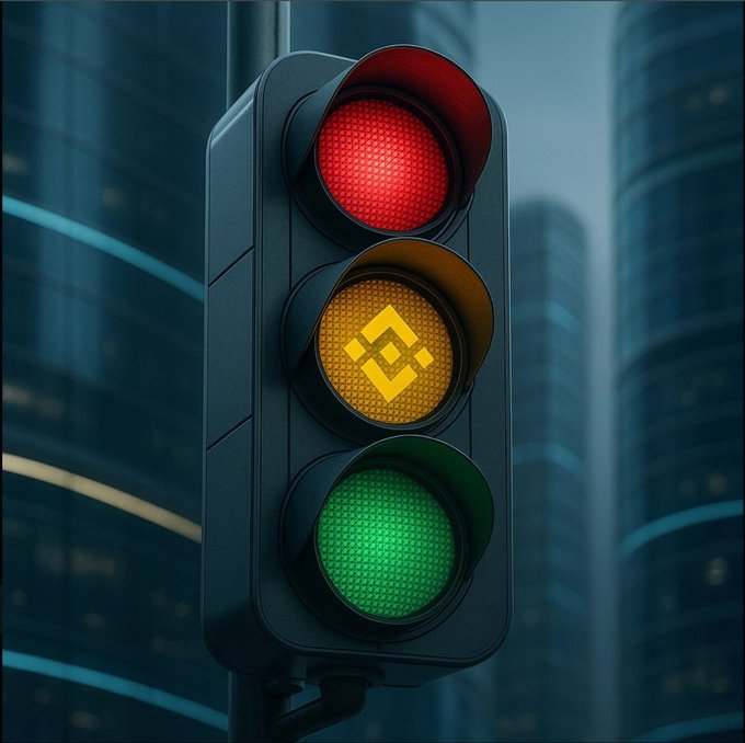 A digital illustration of a traffic light displaying red, yellow (with a Binance logo), and green lights against a futuristic cityscape with skyscrapers.