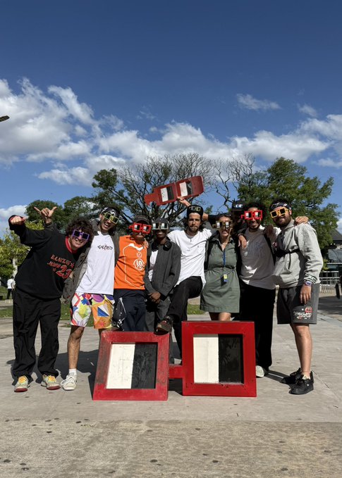 A group of people wearing colorful 3D-style glasses pose triumphantly with a large red "10" art installation, celebrating the $BASE project on flooor.fun, with the engaged community ready for the next milestone.