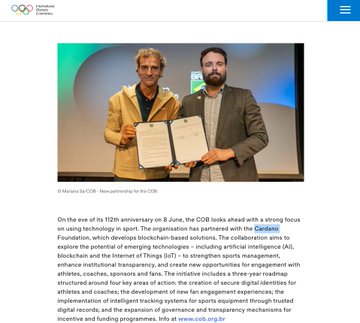 The image shows two men standing next to each other holding papers, possibly an award or a certificate. The text "ON THE EVE OF IT'S 12TH ANTHROPOGENIC OLYMPIC BOARD" can be seen in the image as well. This suggests that they might have just attended an event related to the Olympic Games, and one of them is holding a document.