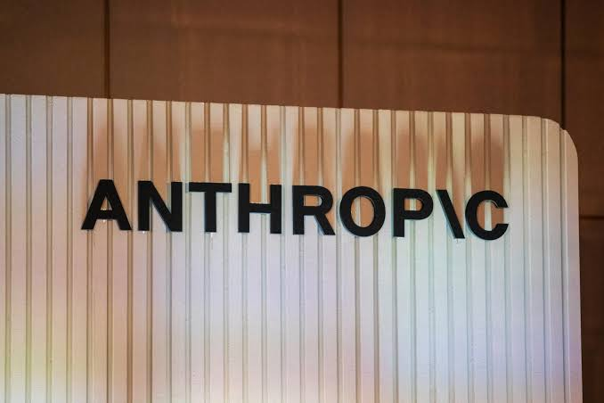 A close-up of a sign displaying the word "ANTHROPIC" in bold black letters on a light, vertically-striped background, representing the AI company central to the discussion about its potential IPO.